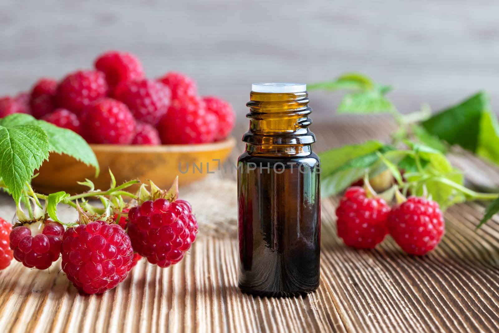 A bottle of raspberry seed oil with fresh raspberries by madeleine_steinbach