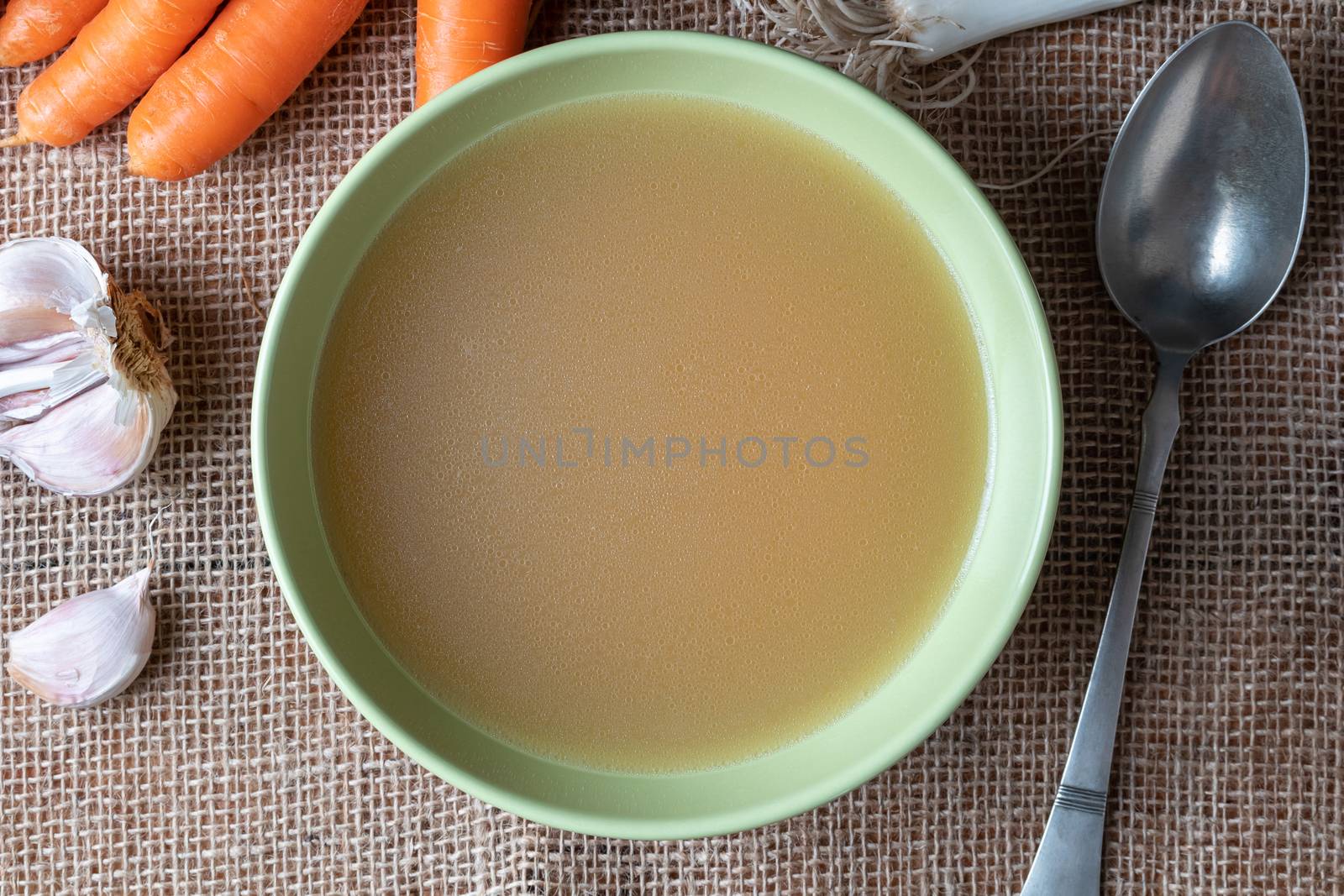 Chicken bone broth in a green plate, top view