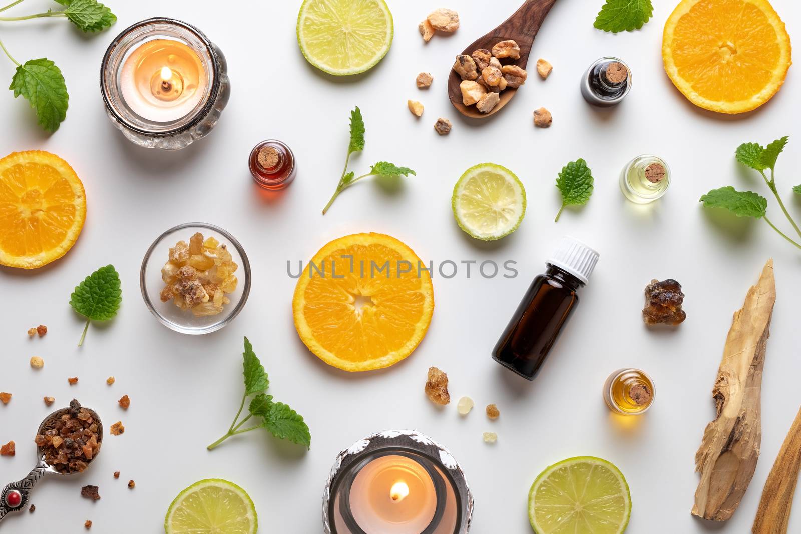 Bottles of essential oil with fresh citrus fruit, melissa, myrrh, white sandalwood and other ingredients