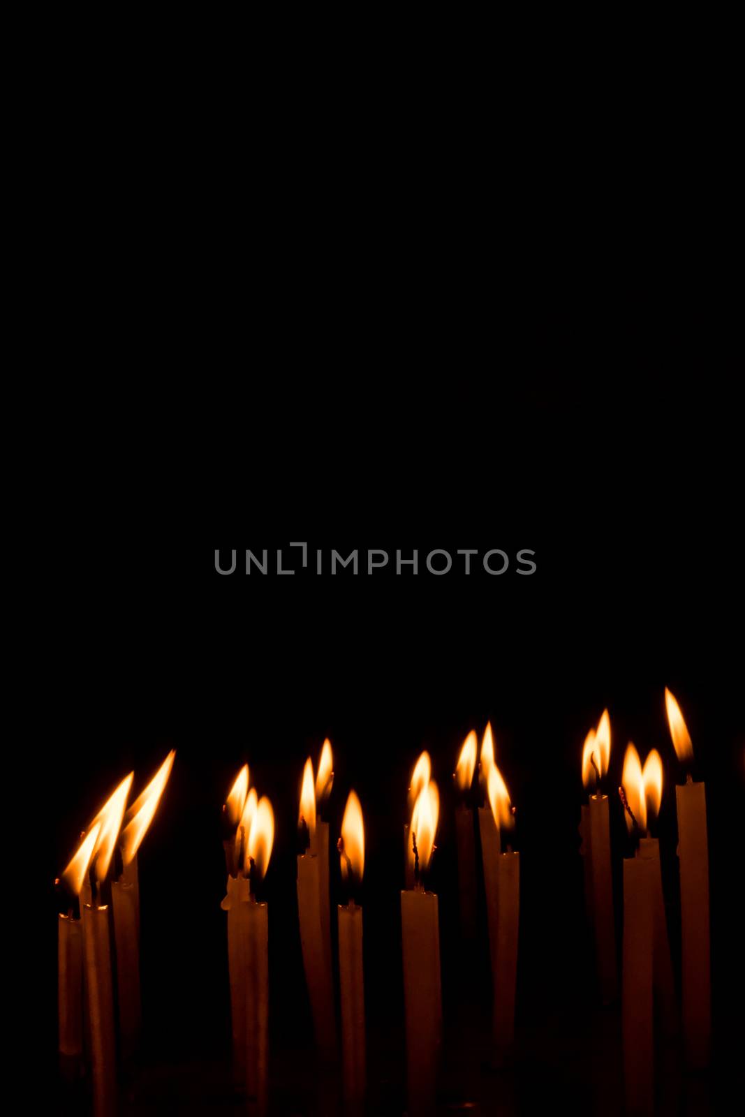 Many christmas candles burning at night on the black background. by sudiptabhowmick