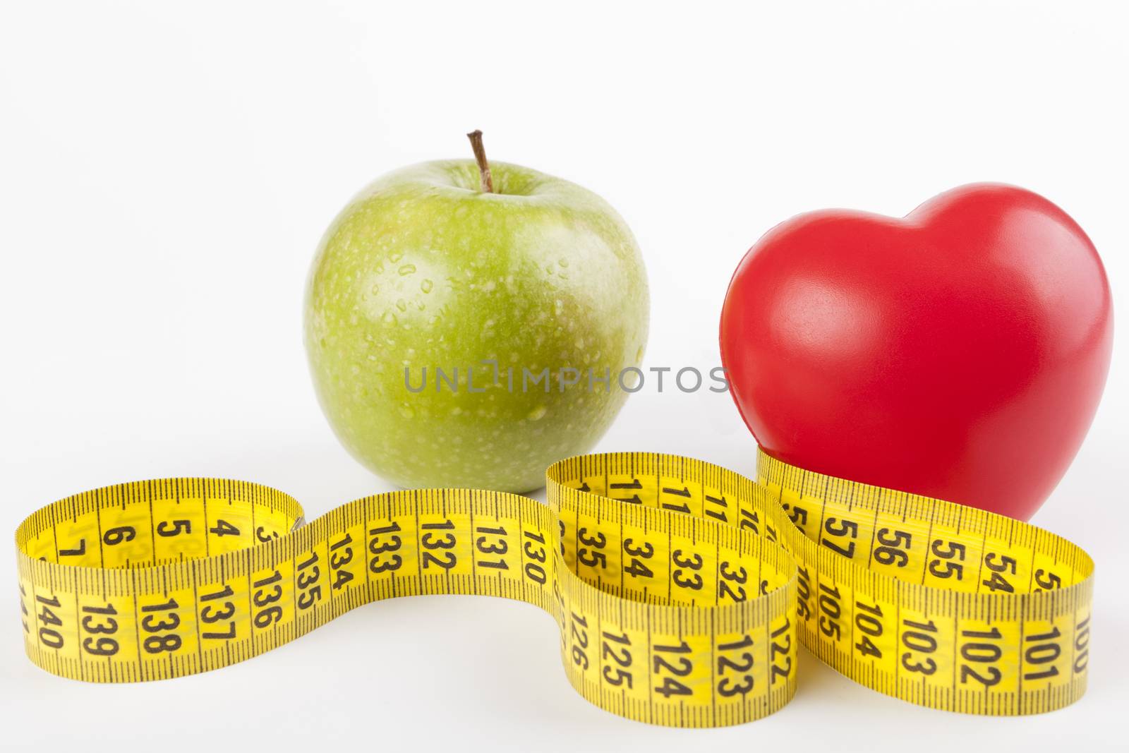 Red heart with green wet apple and yellow mesuring tape isolated on white background