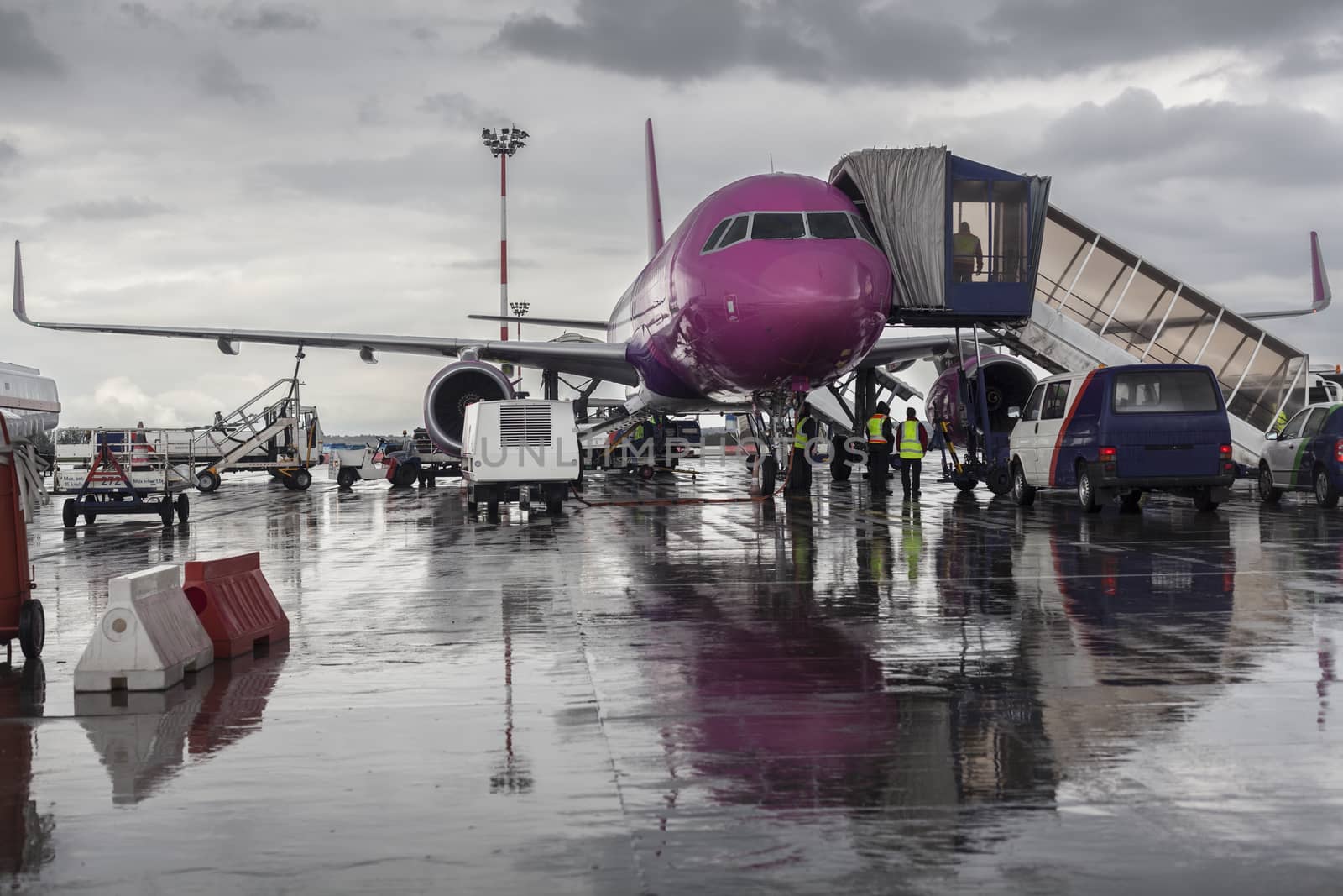 Purple airplane on the ground with maintenance cars around