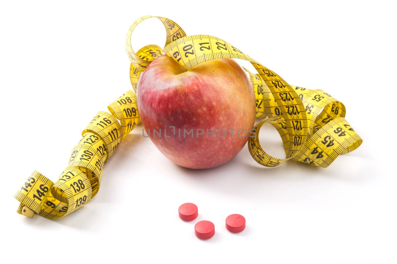 Red Apple with yellow measuring tape and red pills with reflection isolated on white background