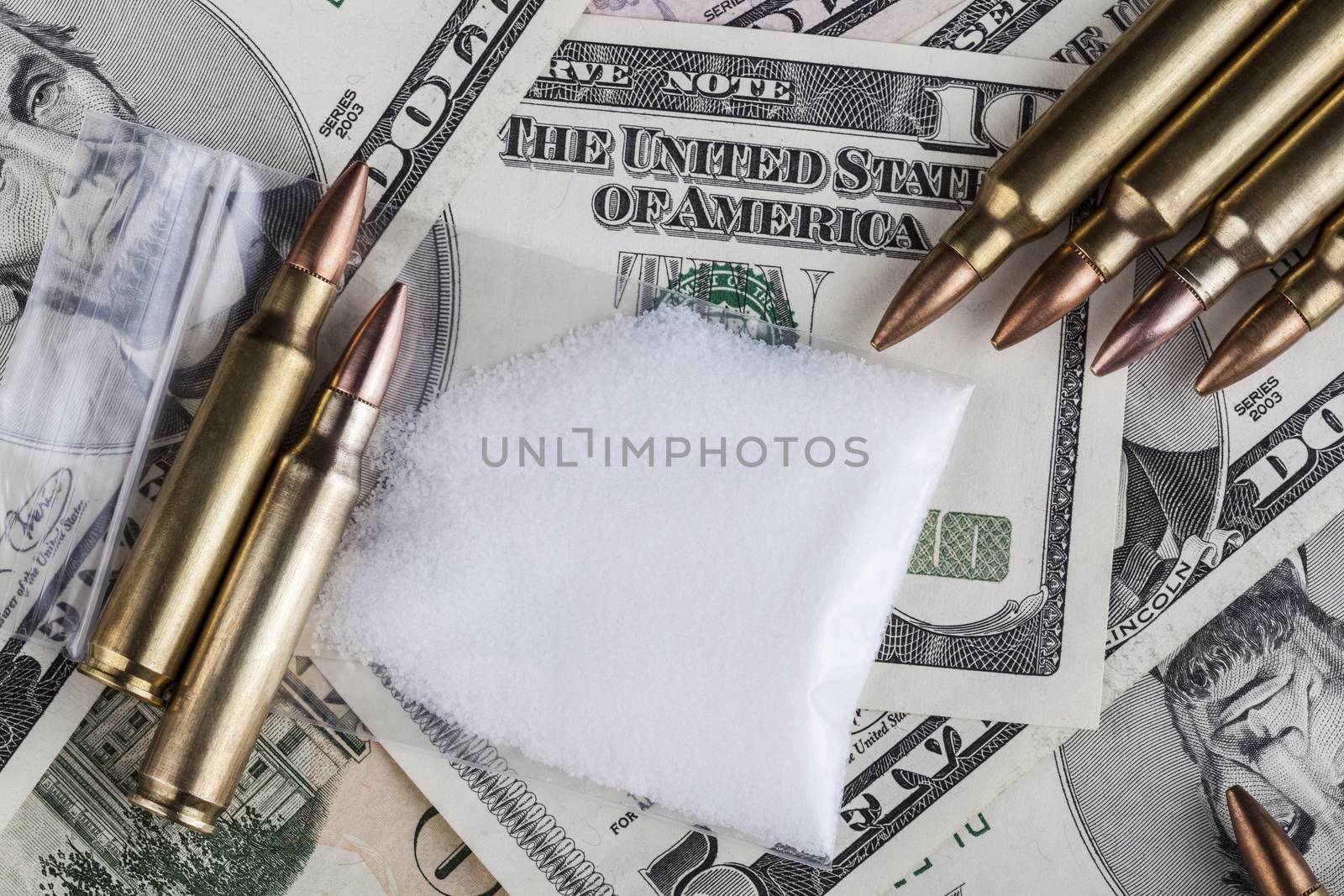 Bullets on dollar banknotes with a bag of white drug powder