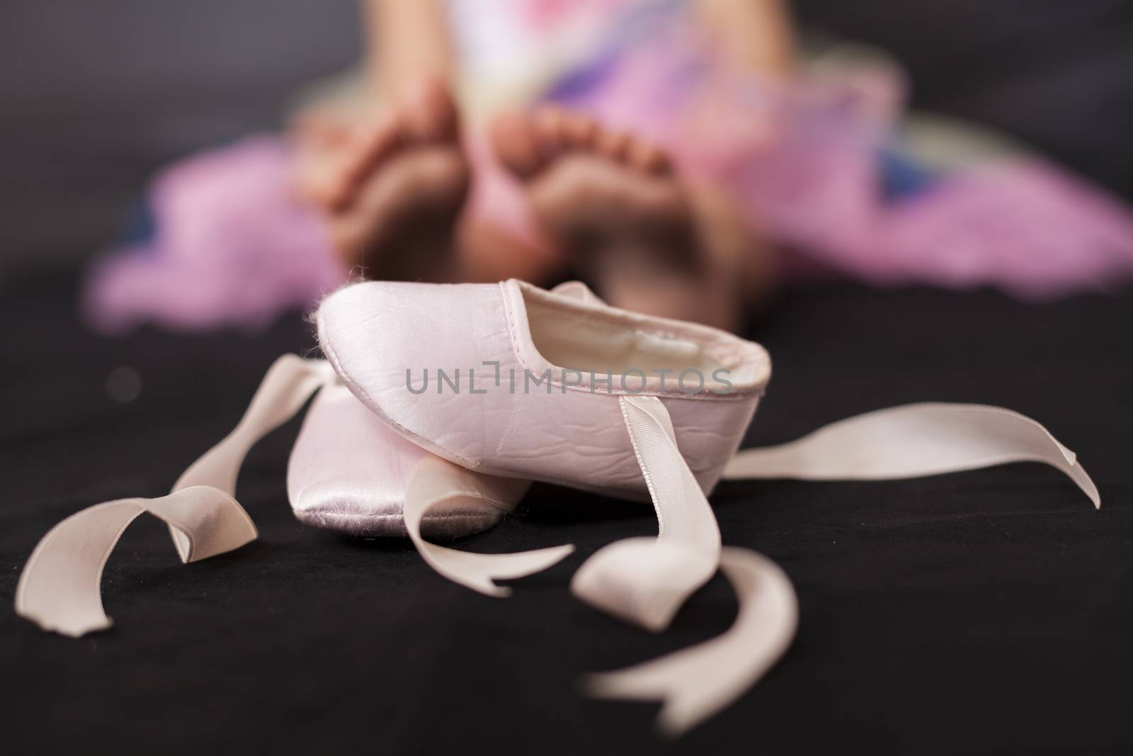 Pink ballerina baby shoes with girl feet in the background