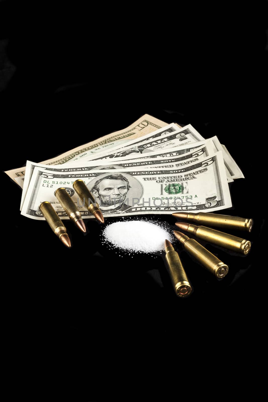 bullets on dollar banknotes with white drug powder on black background