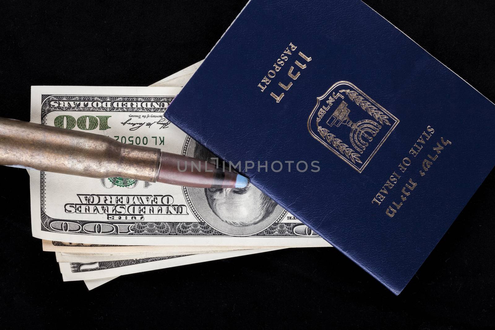 Israelian passport with dollar banknotes and a rifle bullet isolated on black background