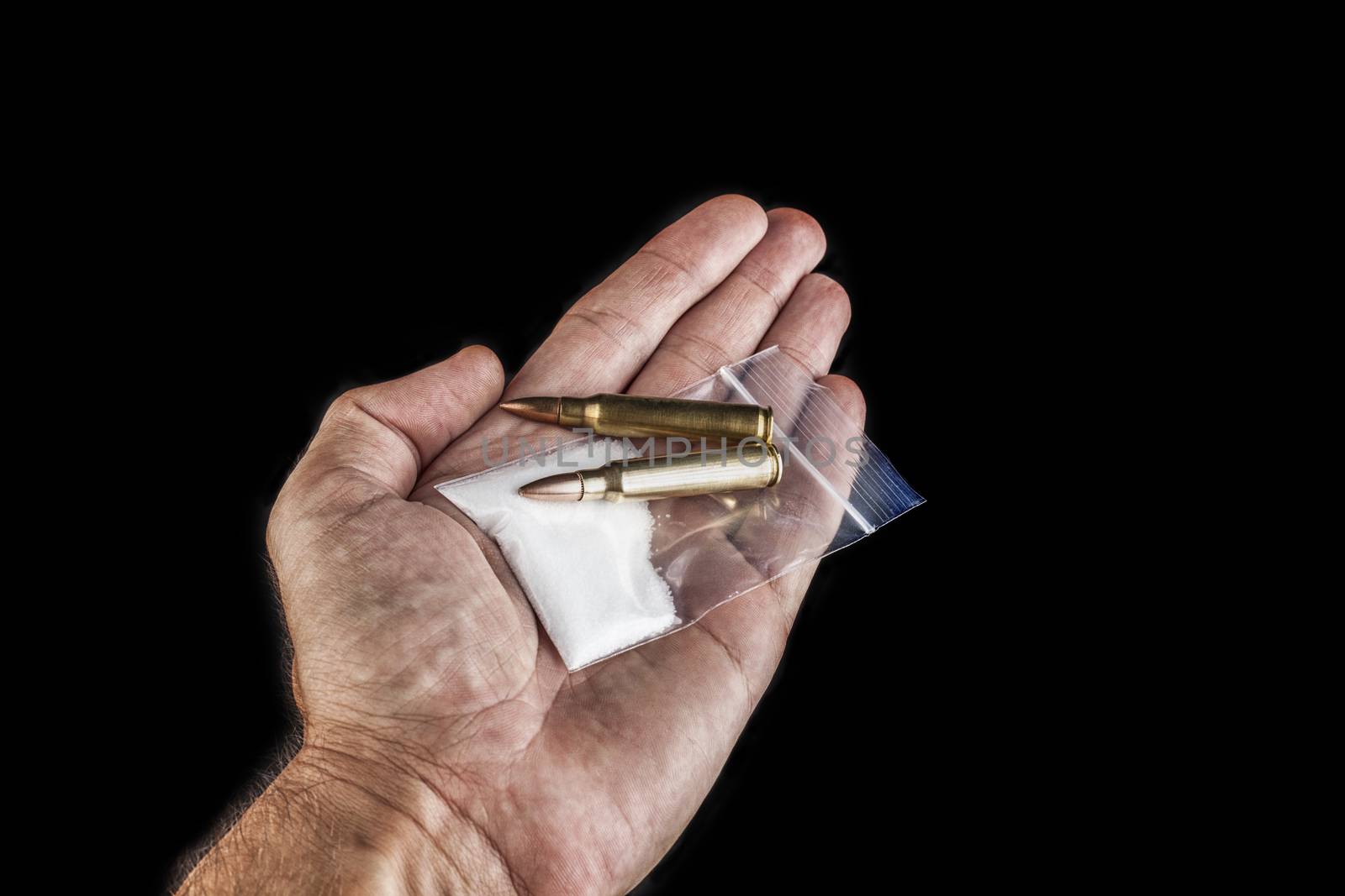 Rifle bullets close-up  in hand on black background with a bag of white drug powder