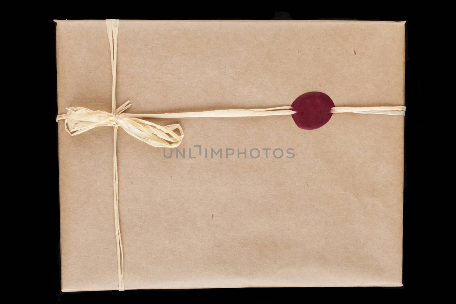 Old brown wrapping paper gift close-up with tied bow and red wax seal