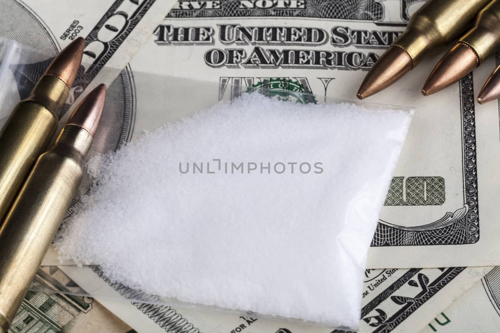 Bullets on dollar banknotes with a bag of white drug powder