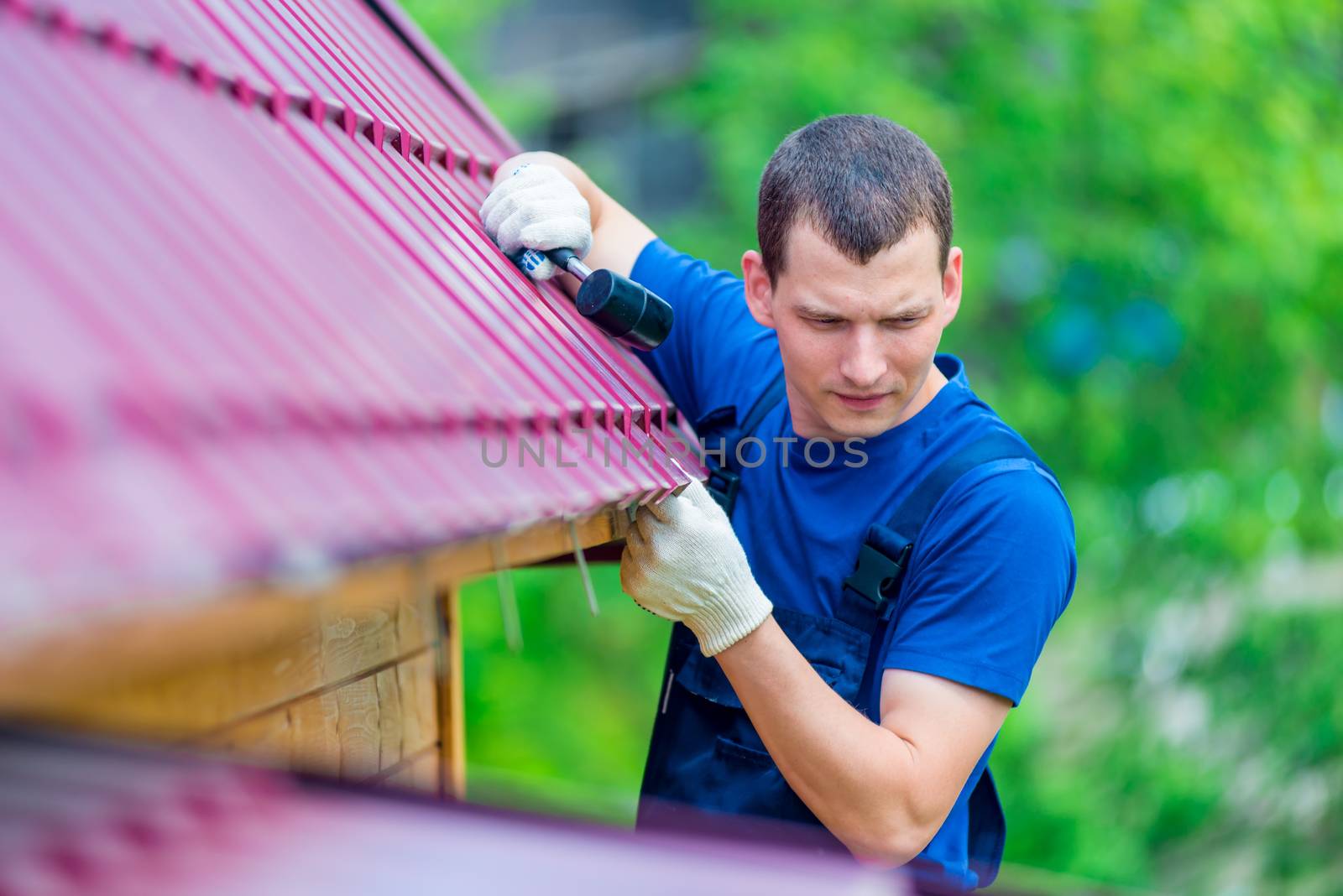 a man with a hammer repairs the roof of a house, shooting outdoo by kosmsos111