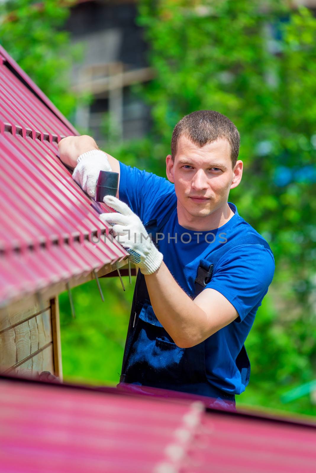 vertical portrait of a man with a hammer repairing the roof of t by kosmsos111