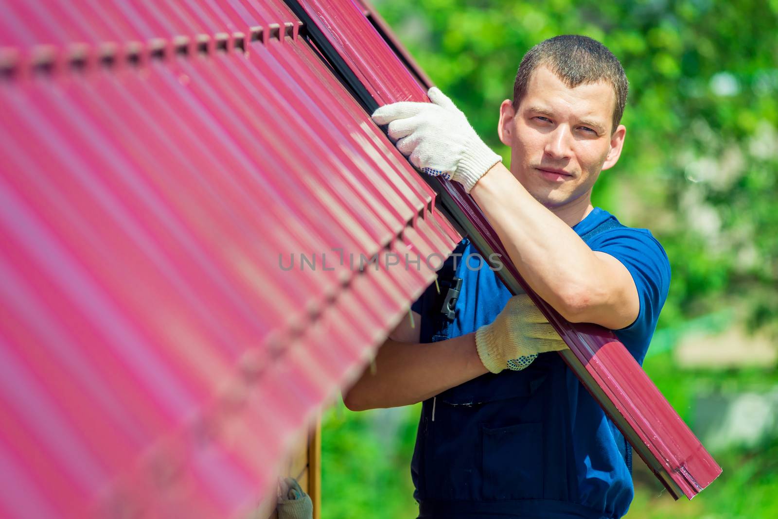 Portrait of repairman in the background of the roof of a private house, is engaged in repair