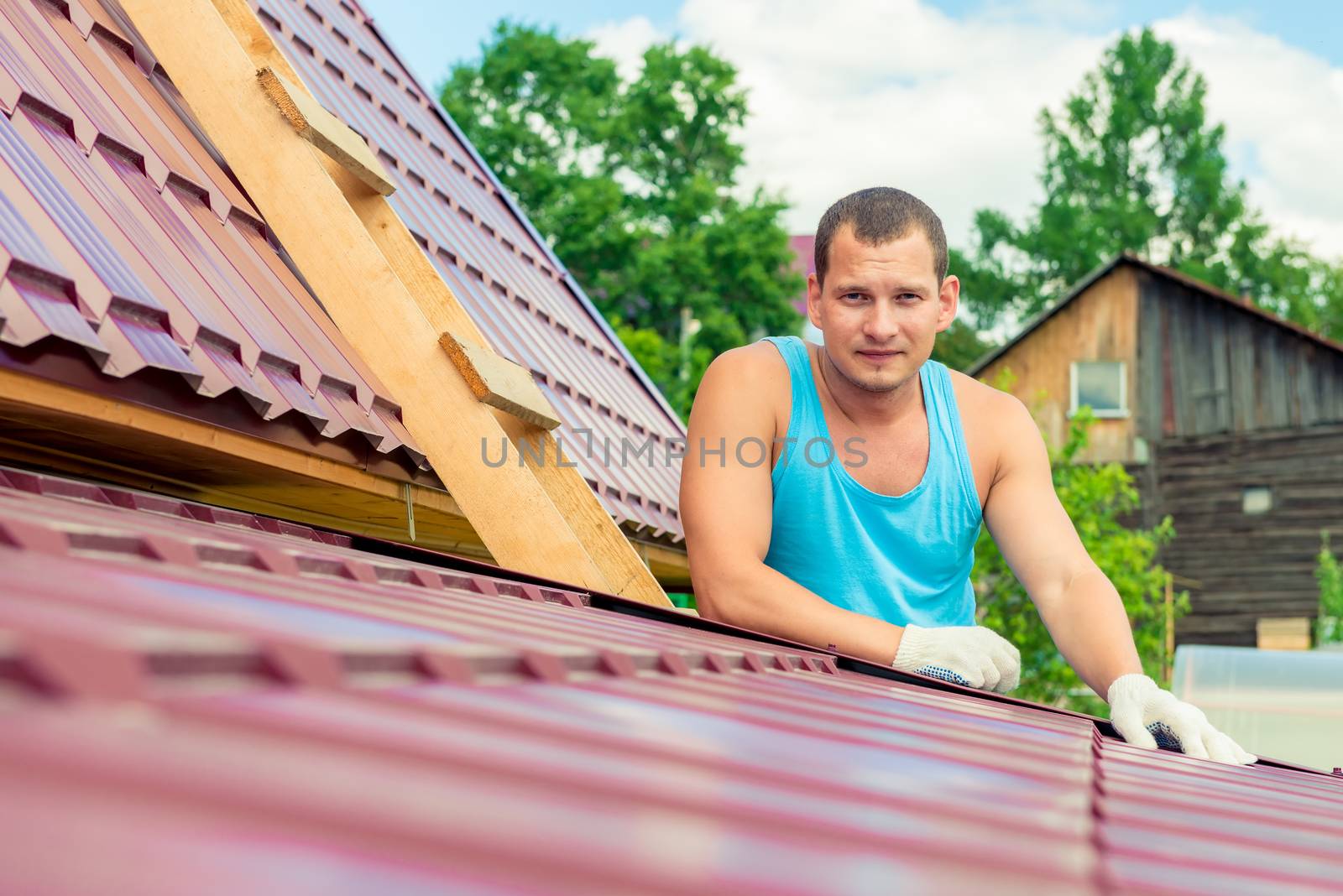 Portrait of a man with a toolbox on the roof of the house during the repair