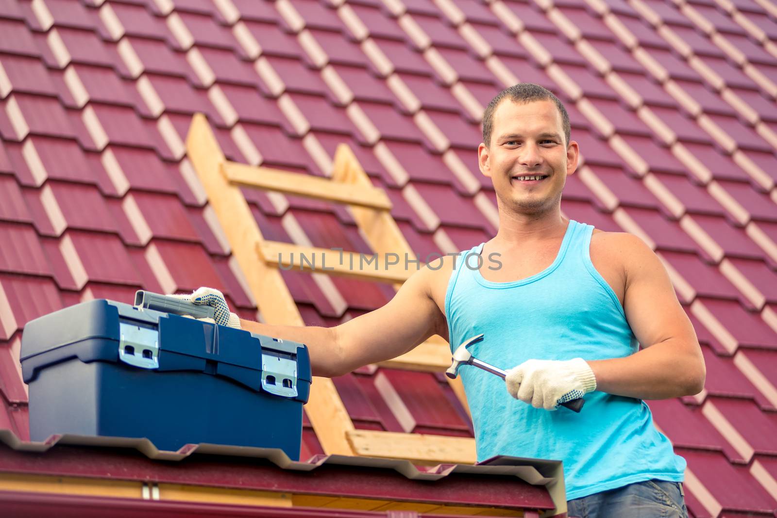 happy portrait of a man with a toolbox on the roof of the house by kosmsos111