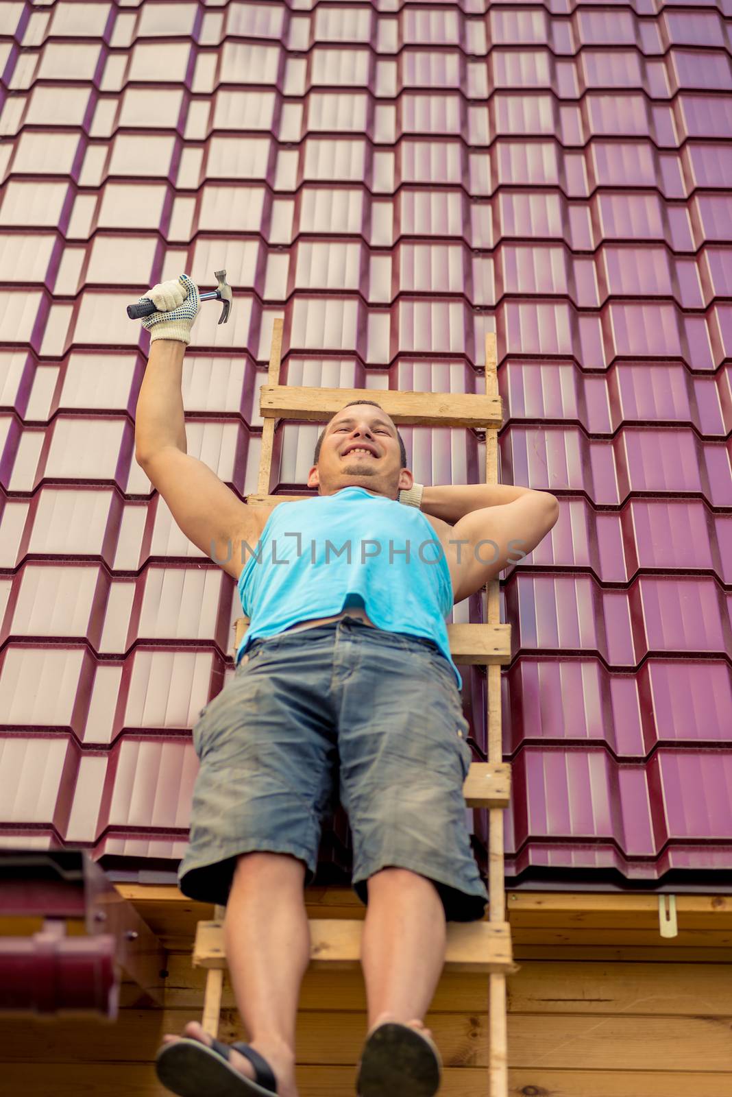 Repairman on a ladder on the roof while resting from work