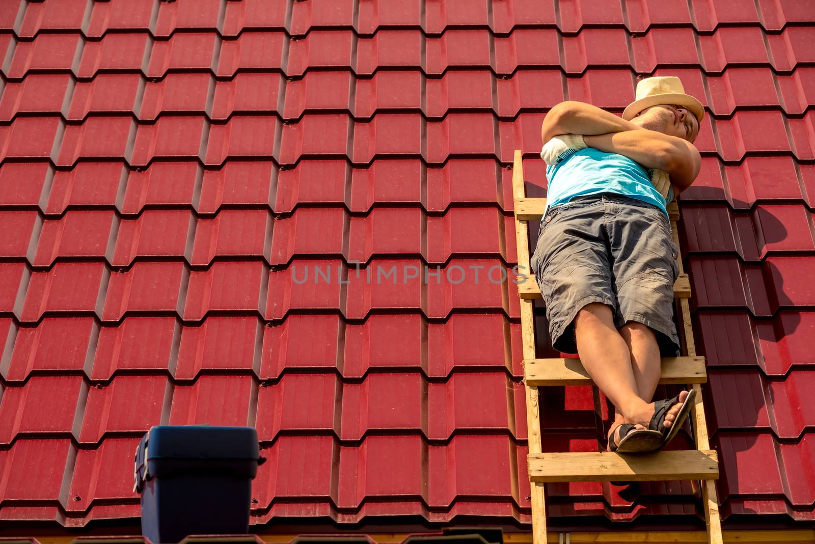 a worker asleep during a break sunbathing on the stairs on the roof of a house