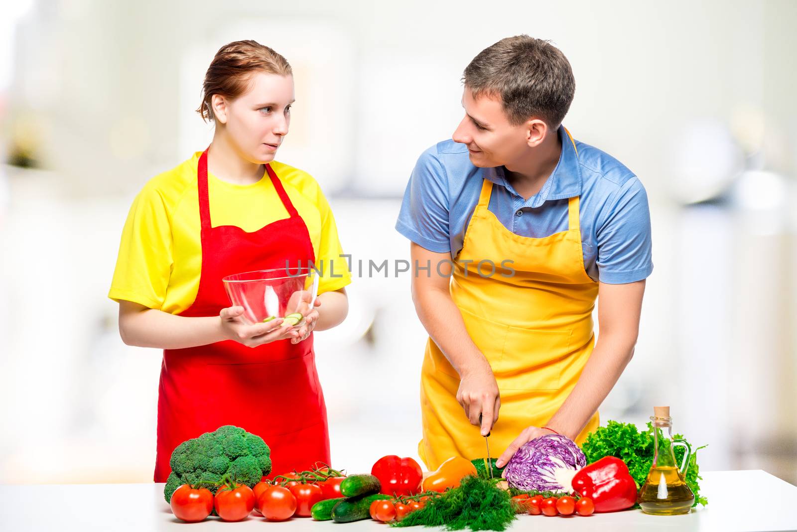 young couple preparing healthy vegetable salad in the kitchen by kosmsos111