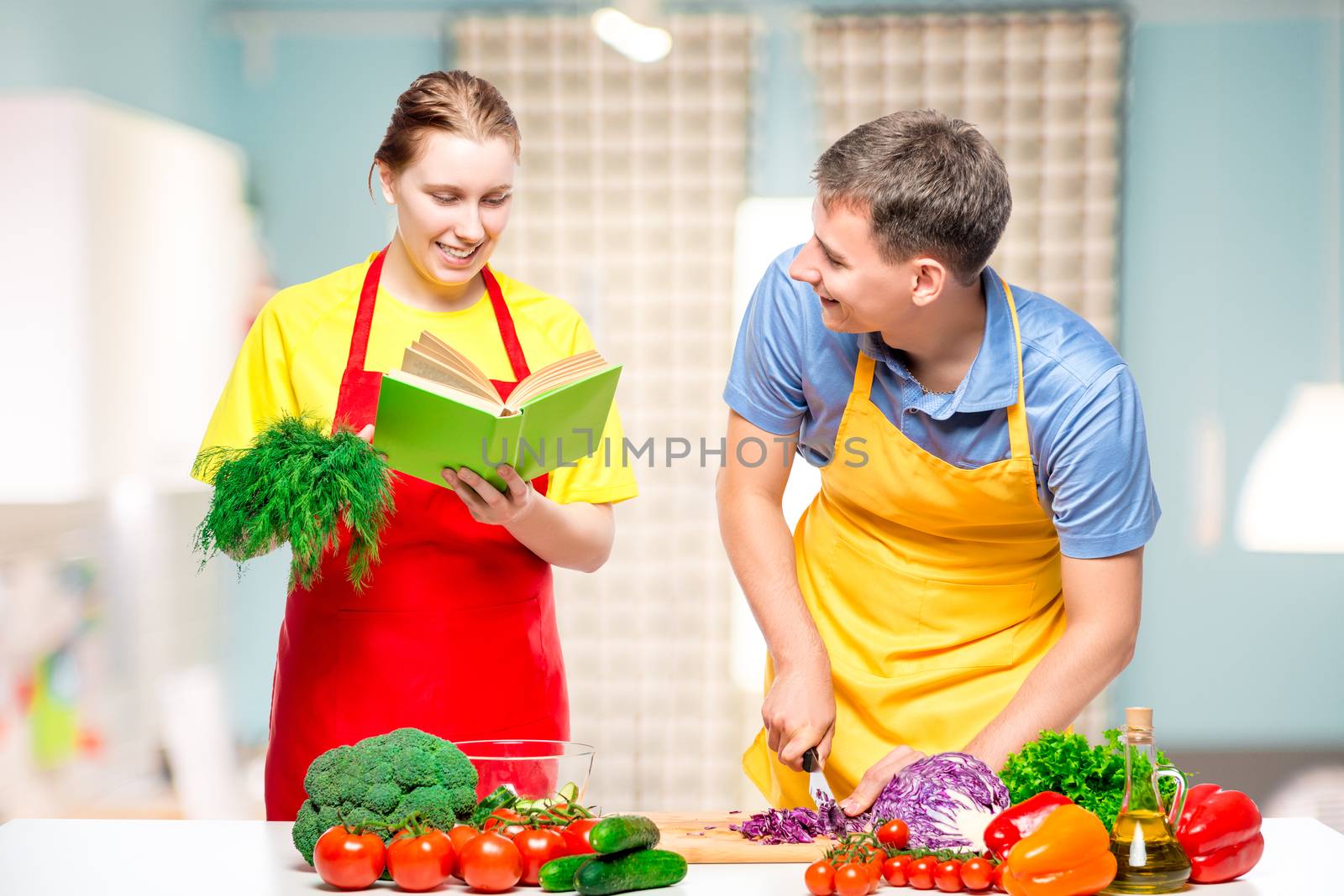 woman with a recipe book, a man cuts vegetables cooked together by kosmsos111