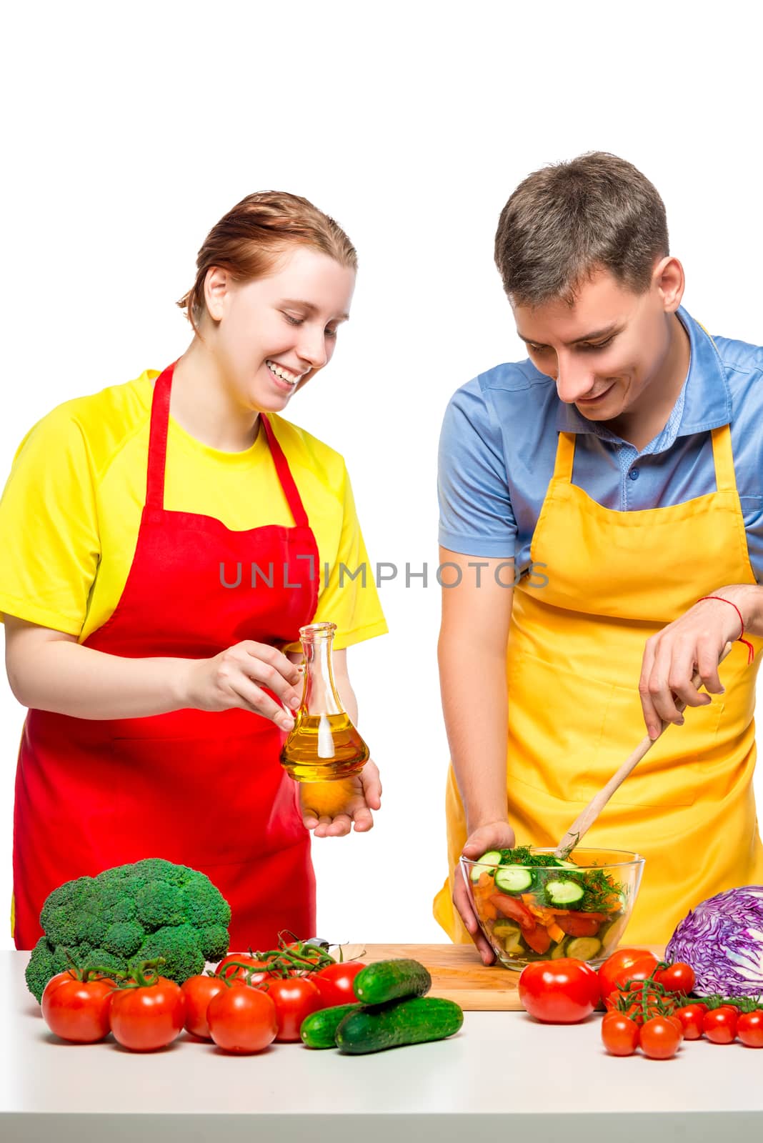 portrait of happy couple while cooking vegetable salad on white background