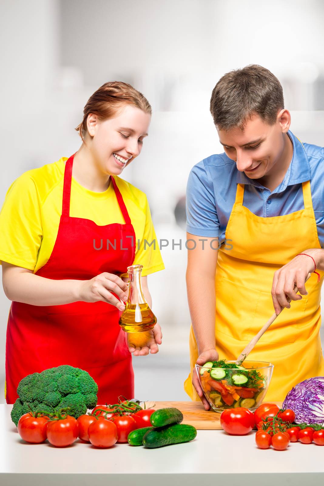 man mixes vegetable salad, wife with olive oil in his hands, portrait in the kitchen