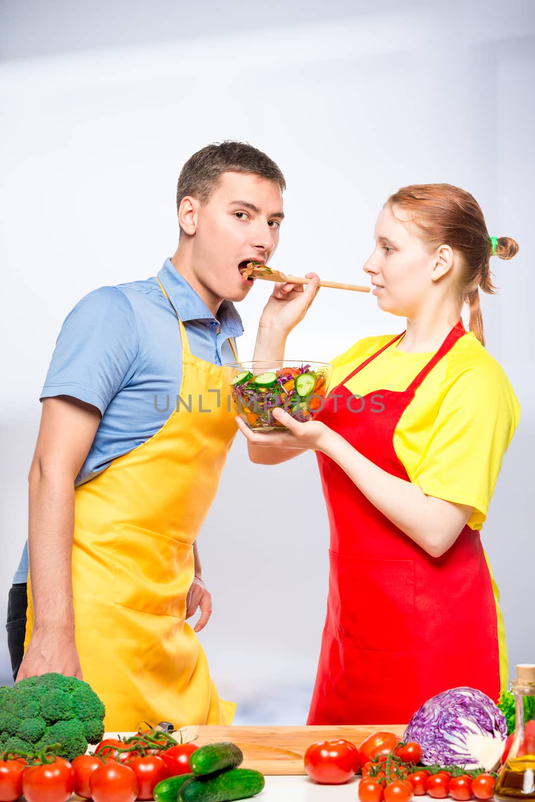 wife treats a man with fresh vegetable salad, a pair of aprons i by kosmsos111