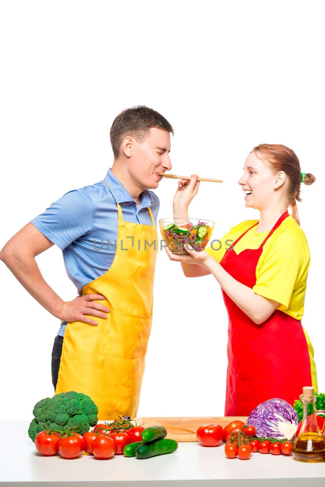 girl treats her lover with fresh vegetable salad, which they cooked together on a white background