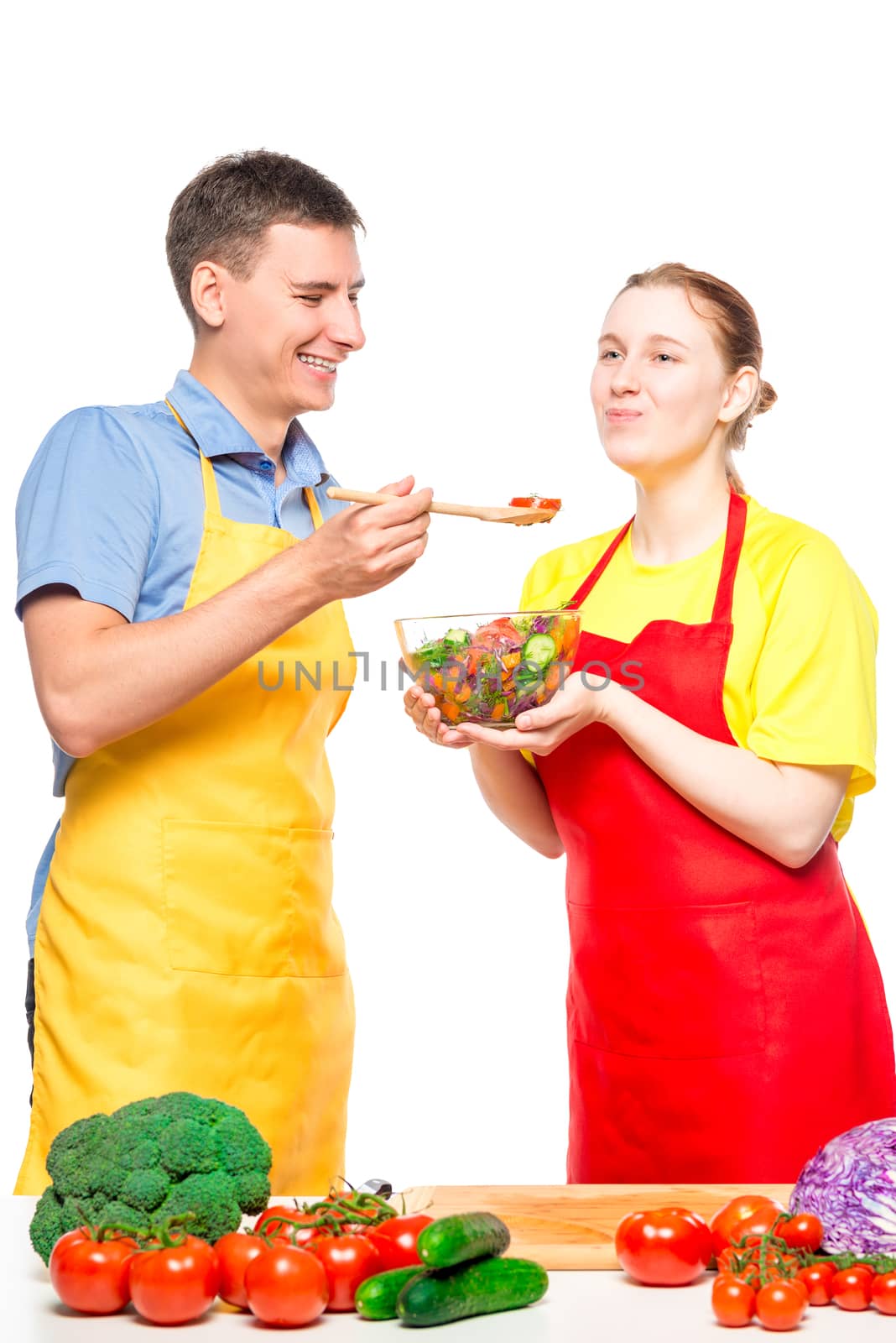a man treats his beloved with fresh vegetable salad, which they cooked together on a white background