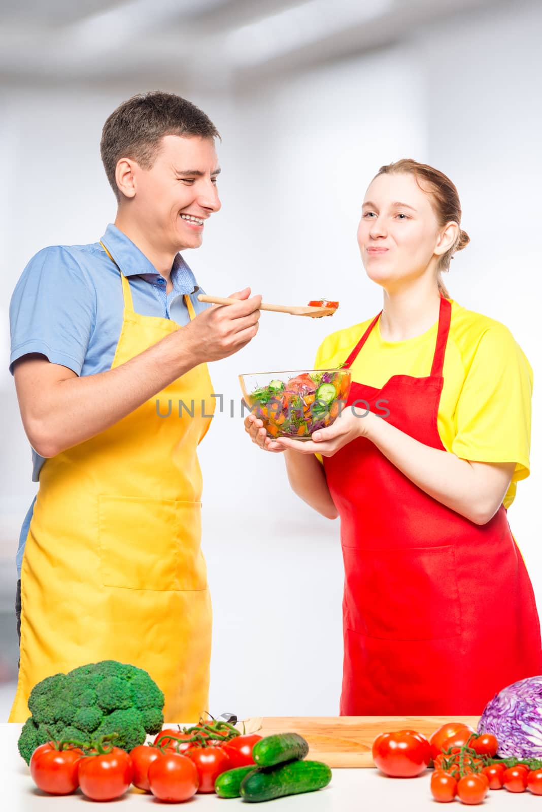 man treats his beloved with fresh vegetable salad, which they cooked together in the kitchen