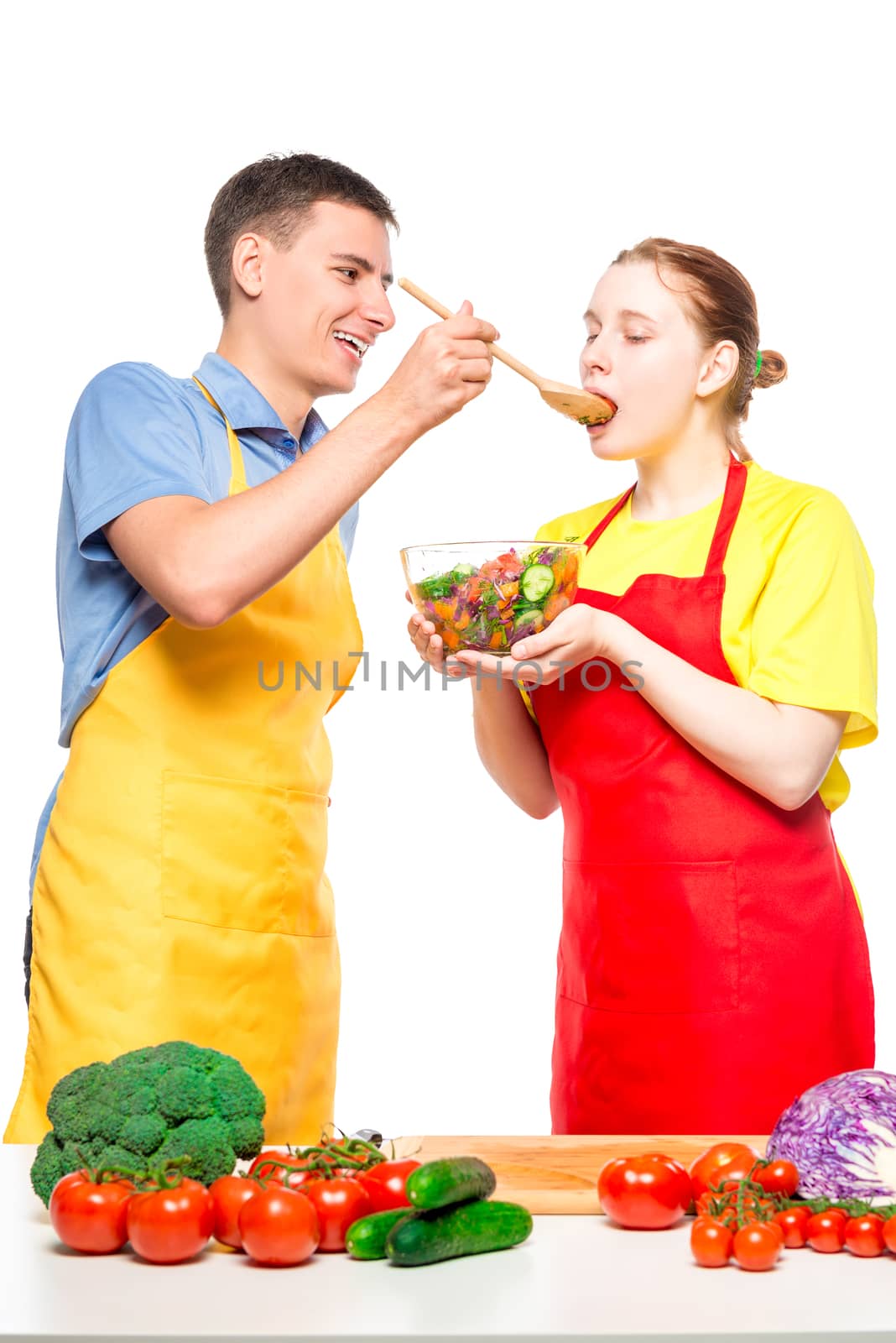 a man treats a girl with fresh vegetable salad, which they cooked together on a white background