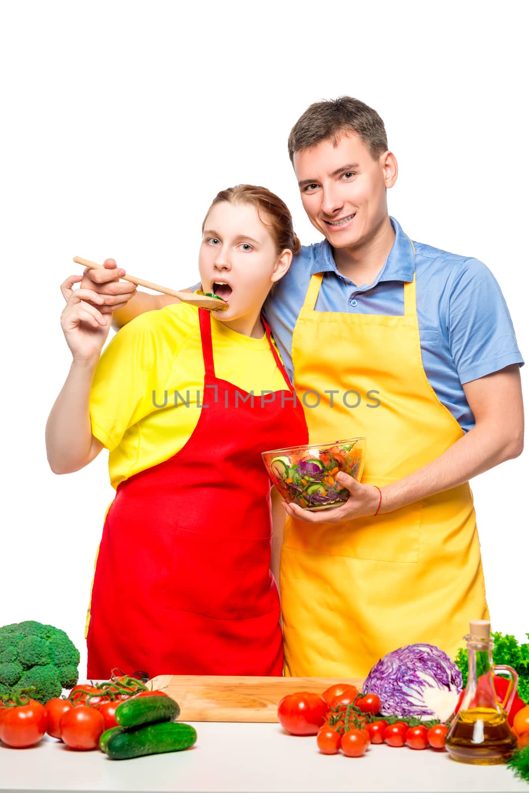 young couple on white background posing with vegetable salad in bowl