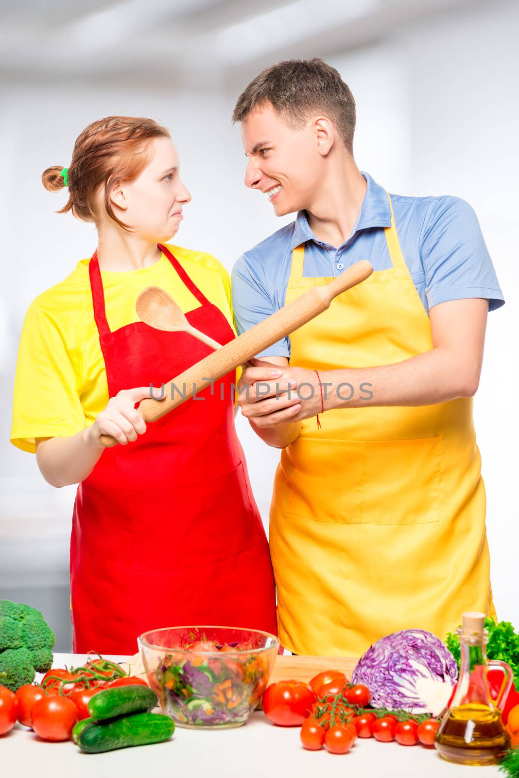 couple fighting kitchen utensils while cooking salad in the kitc by kosmsos111