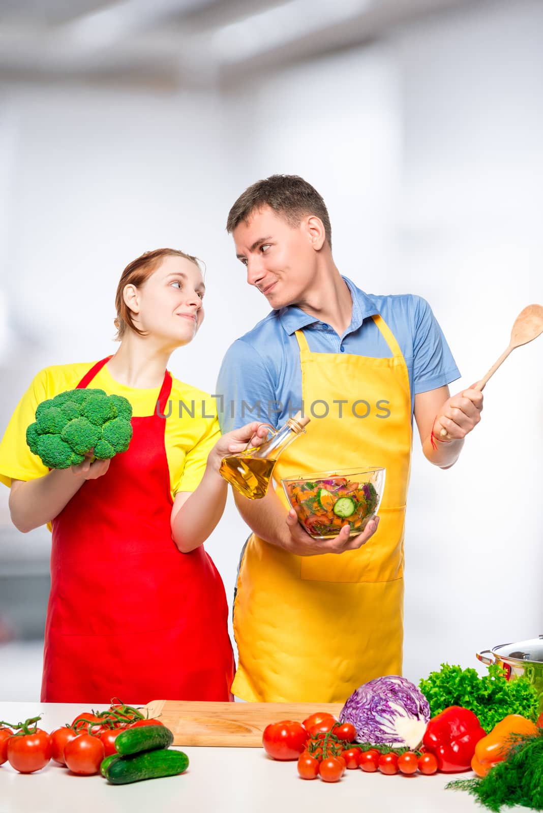 A young couple looks at each other in love while cooking vegetab by kosmsos111