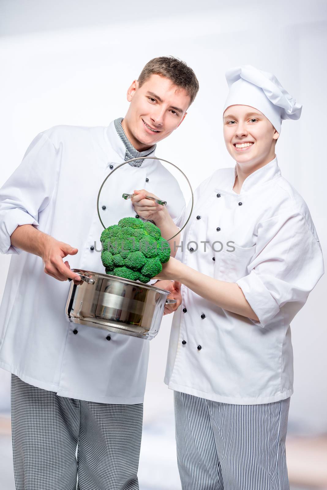 vertical portrait of fellow cooks with saucepan and broccoli in by kosmsos111