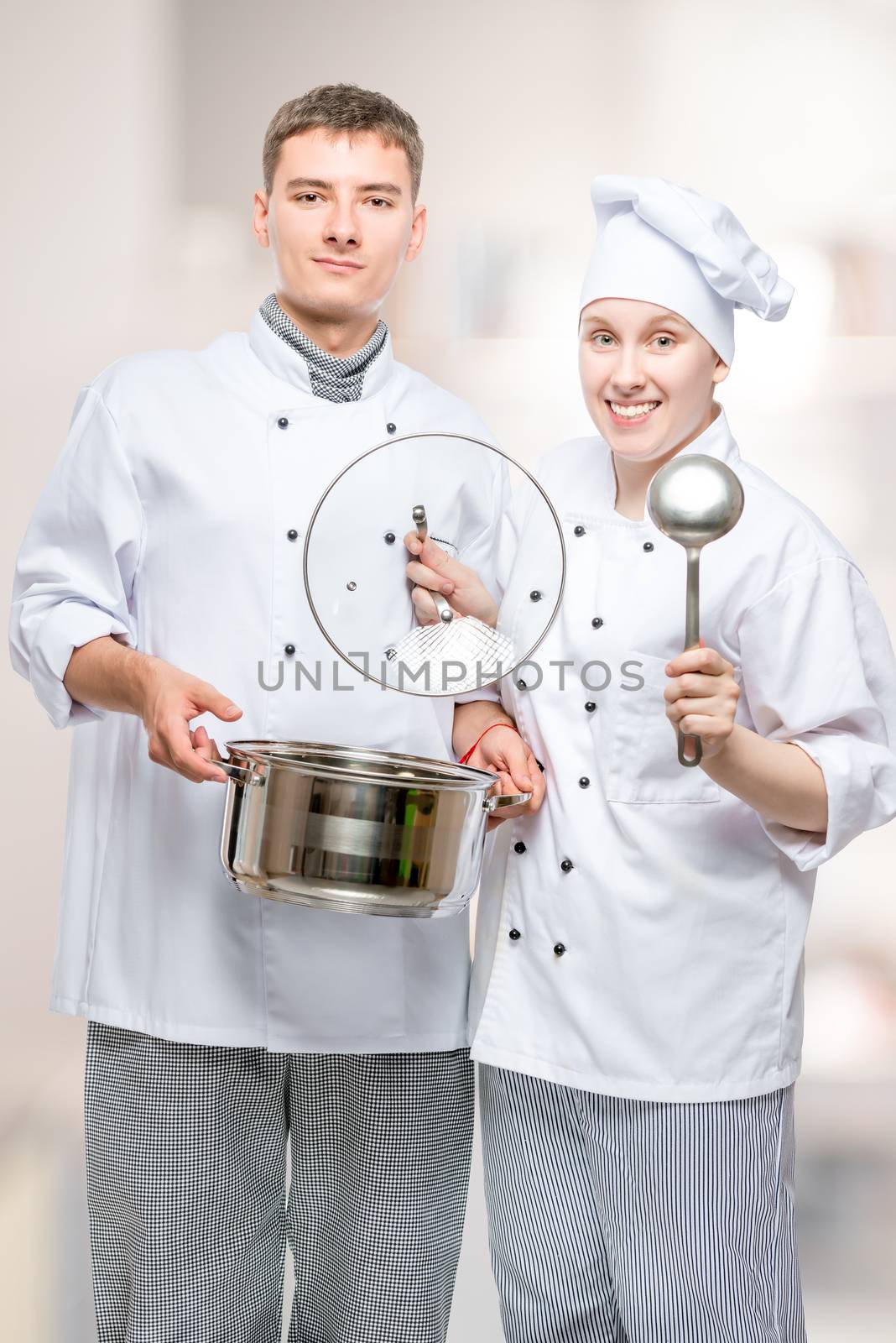 professional chefs with a pan and a ladle in a commercial kitchen posing