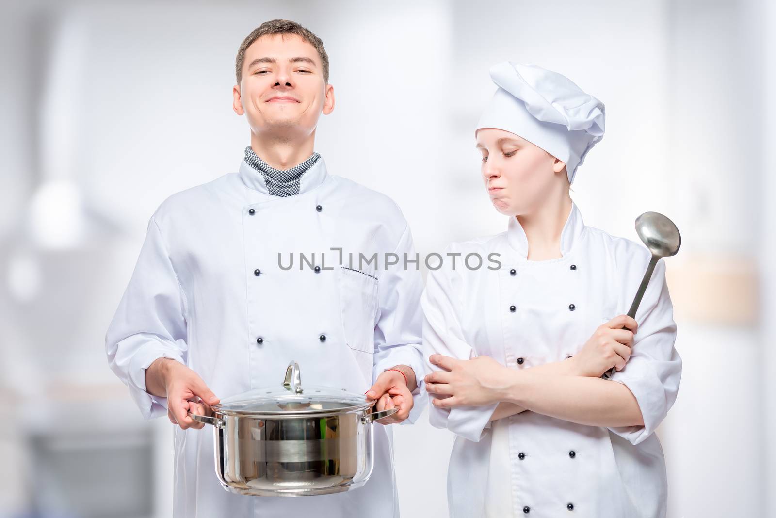 couple in cook costumes posing with a pan on the background of the restaurant's kitchen