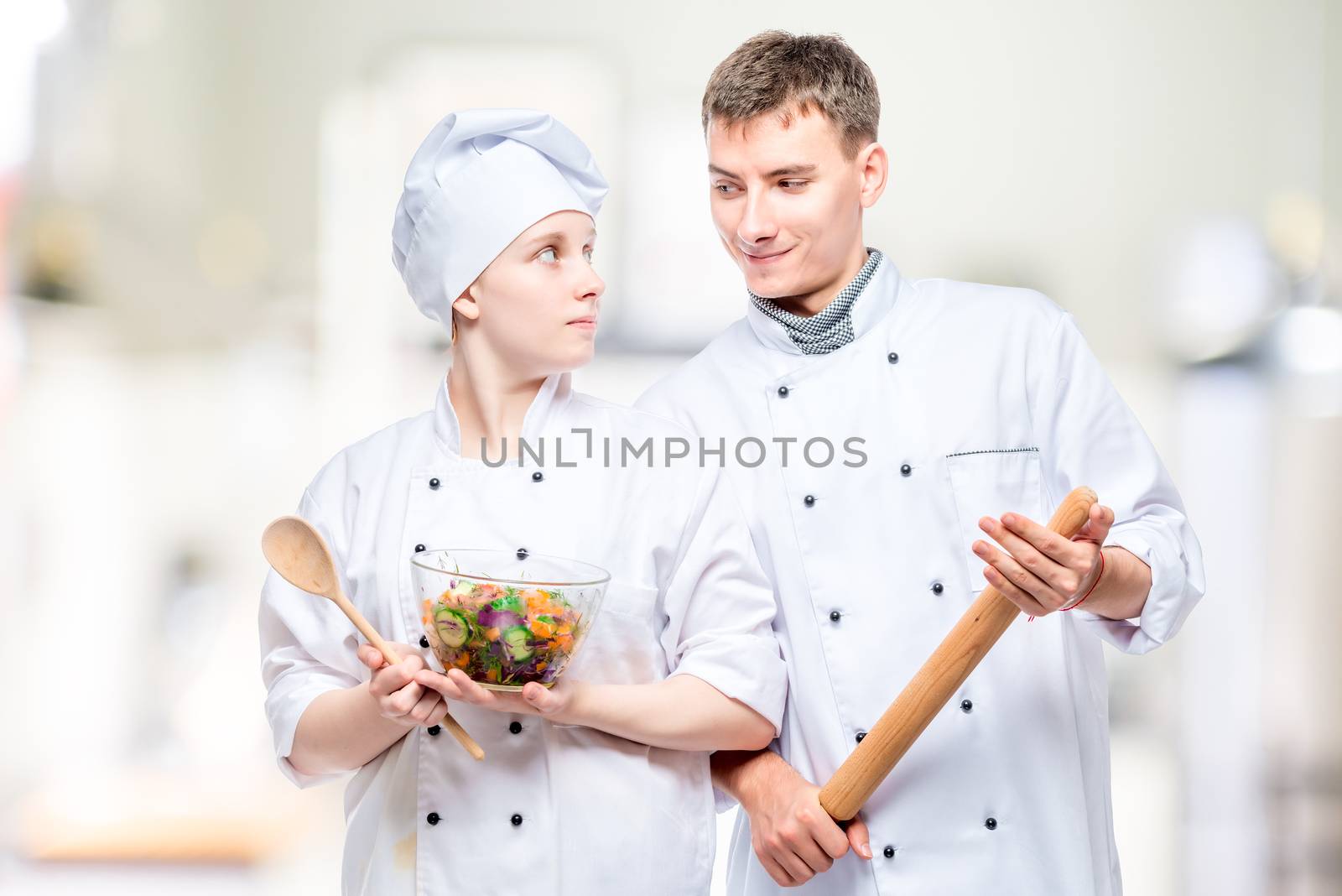 portrait of young professional chefs with a dish on the background of the kitchen