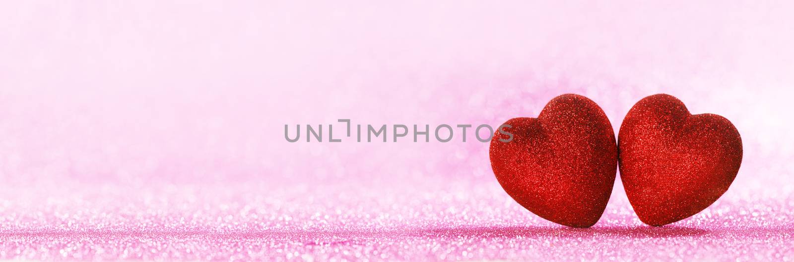 Two red glitter hearts on bright heart lights bokeh background