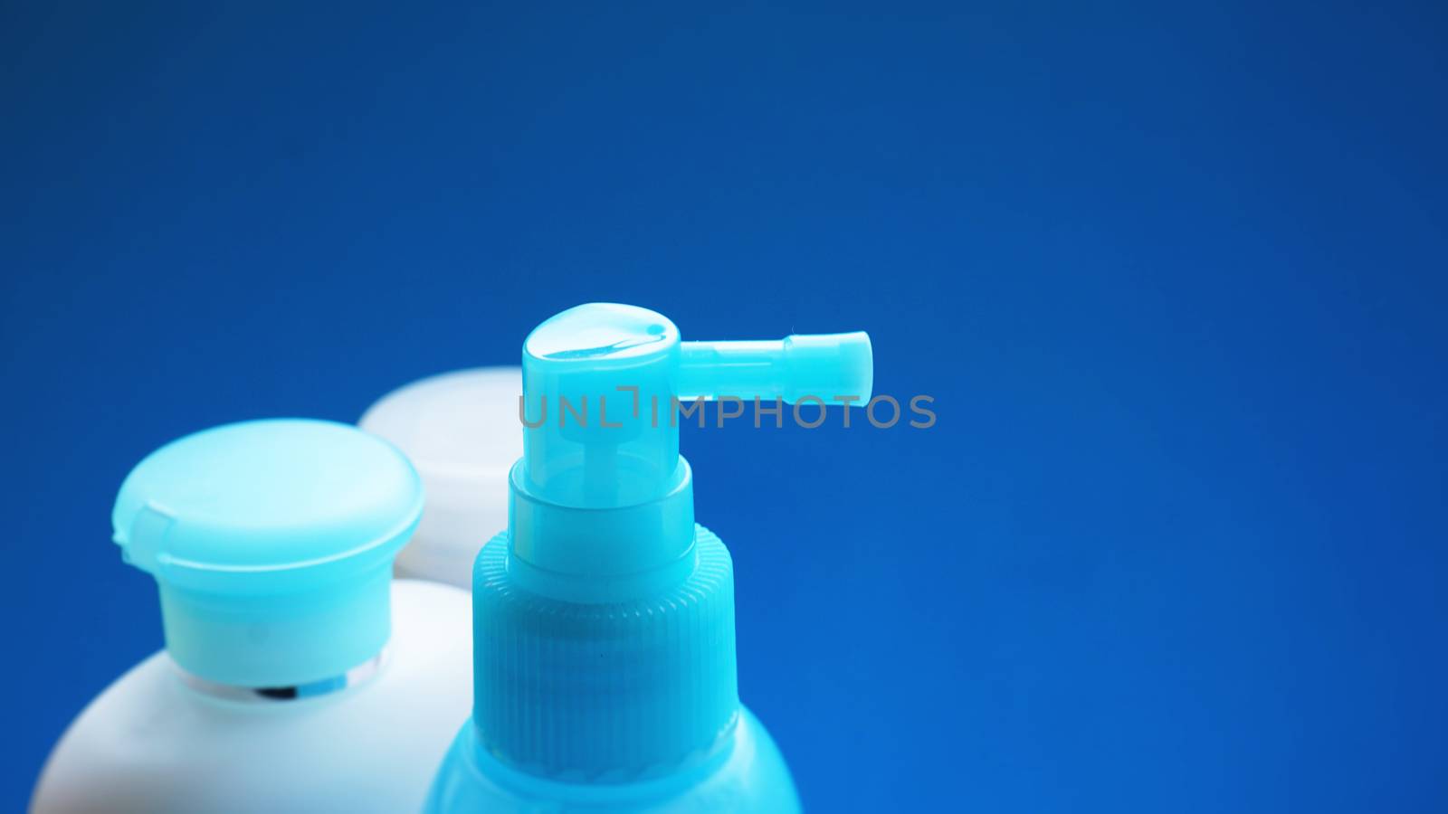 Blue cosmetic tube on blue background. Blank plastic container, packaging design. Copy space photography.