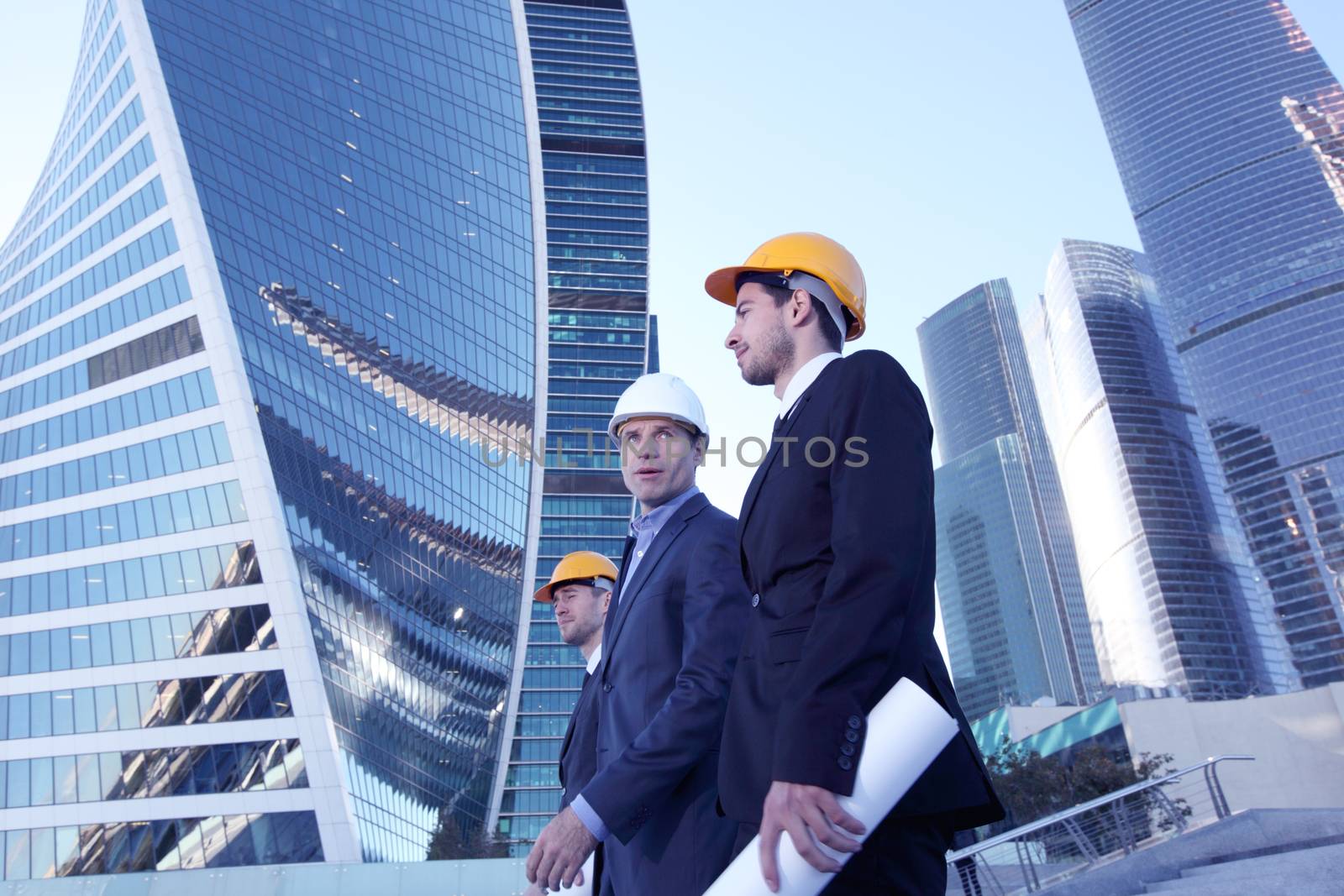 Architects with blueprint at skyscrapers background