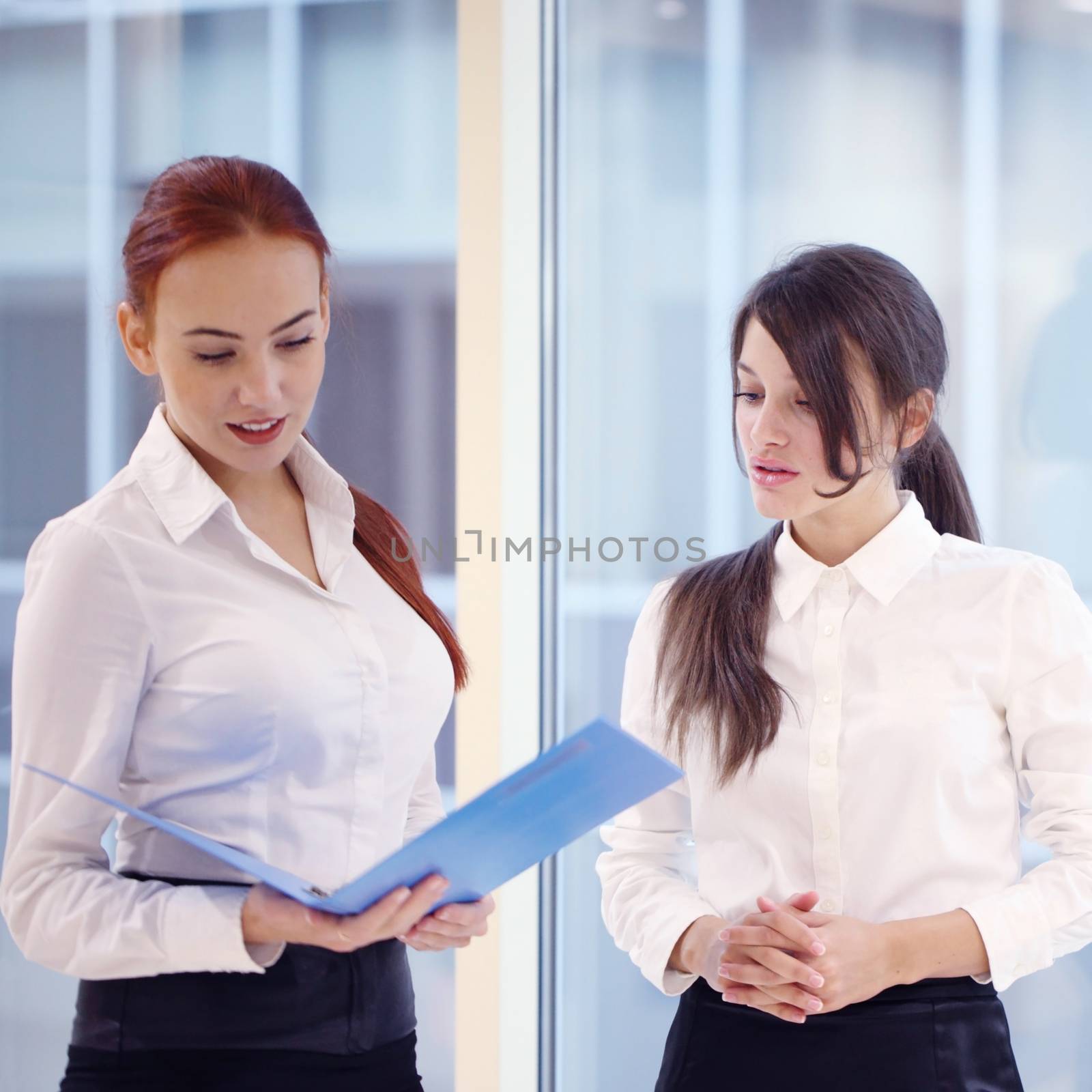 Two young beautiful businesswomen having meeting in modern office
