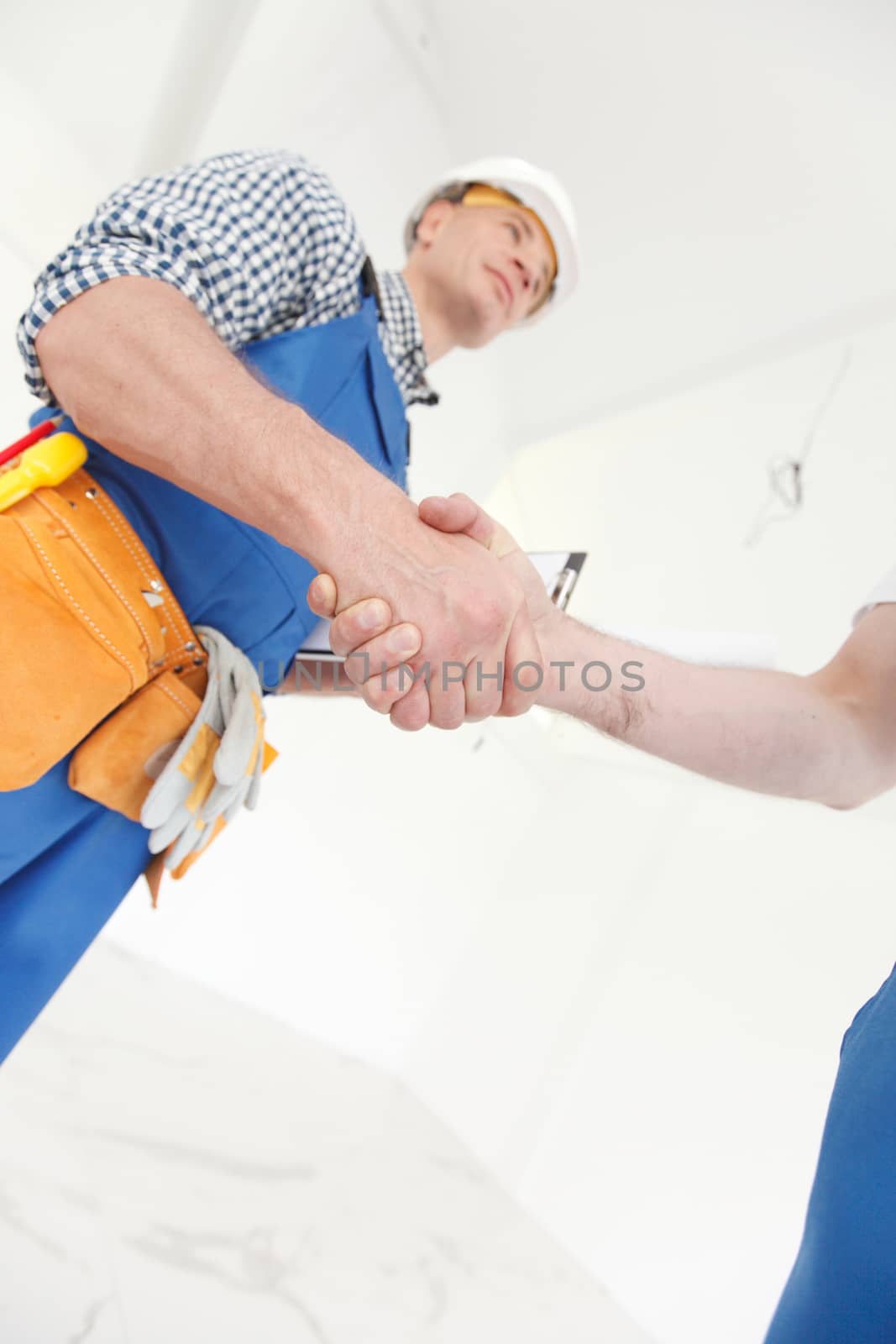 Two construction workers shaking hands, deal is finished concept