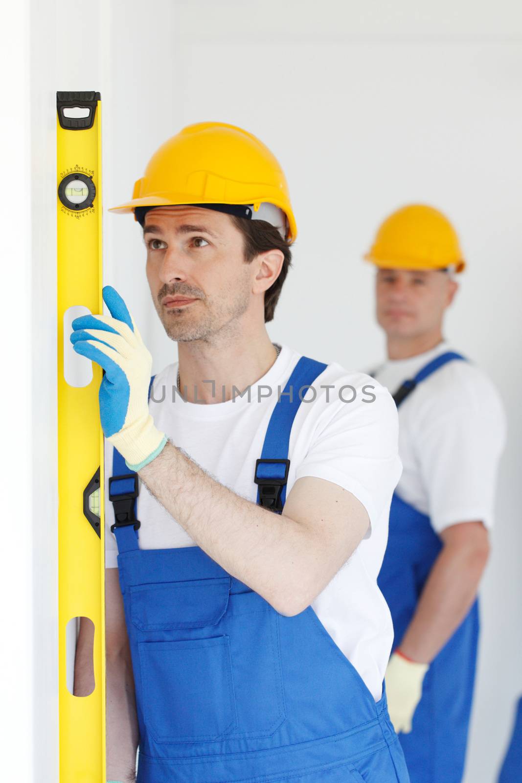 Team of workmen align wall using tools