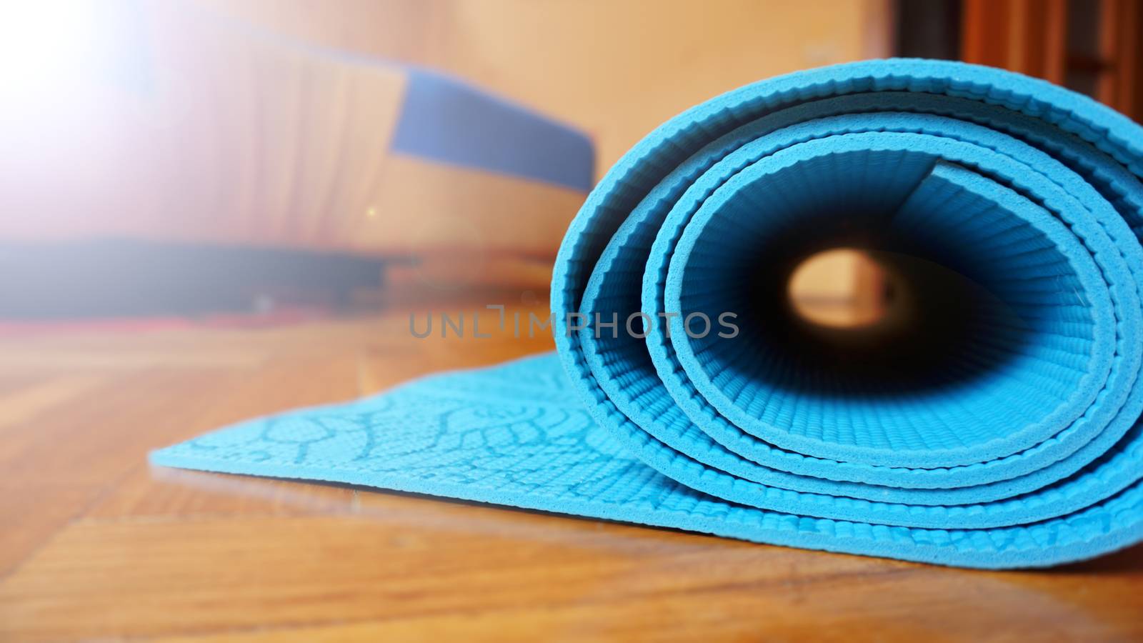 Close up of yoga, fitness floor mat at home in a roll. Yoga props and accessories, aqua turquoise mat. Healthy lifestyle concept