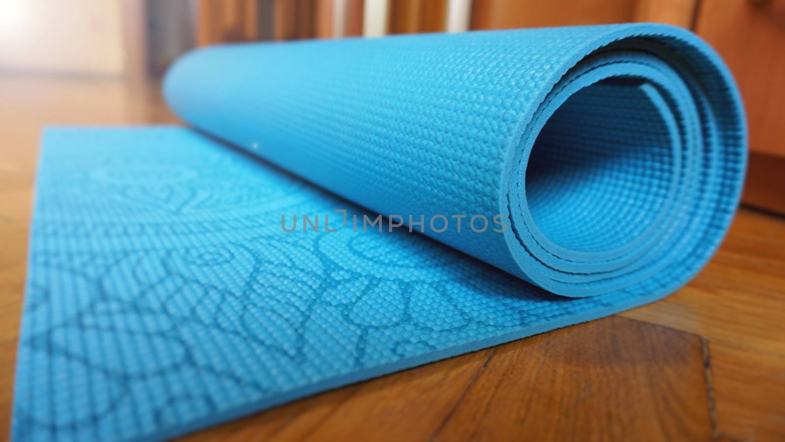 Close up of yoga, fitness floor mat at home in a roll. Yoga props and accessories, aqua turquoise mat. Healthy lifestyle concept