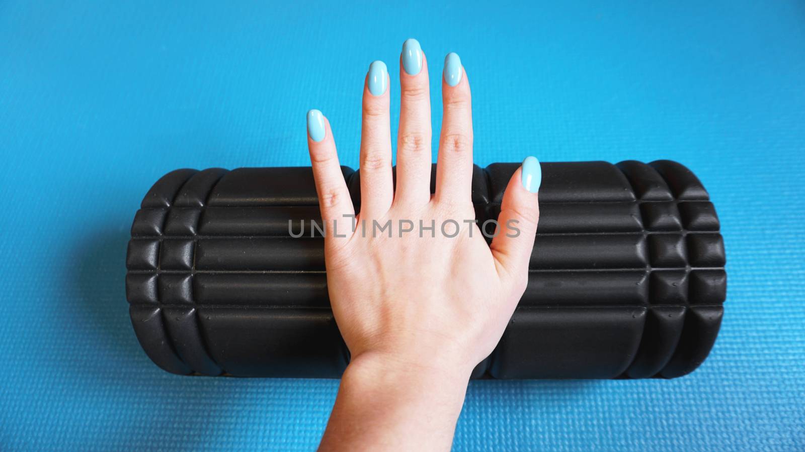 Foam Roller Gym Fitness Equipment Blue background self Myofascial Release - MFR. Hand holds a roller. How to choose equipment for sports