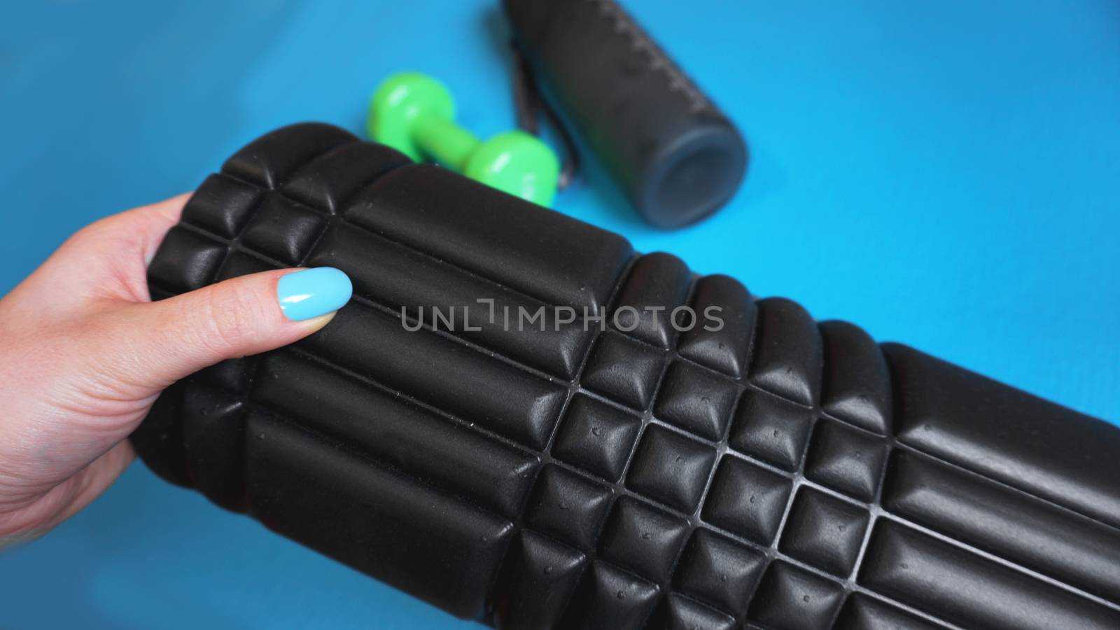 Foam Roller Gym Fitness Equipment Blue background self Myofascial Release - MFR. Hand holds a roller. How to choose equipment for sports