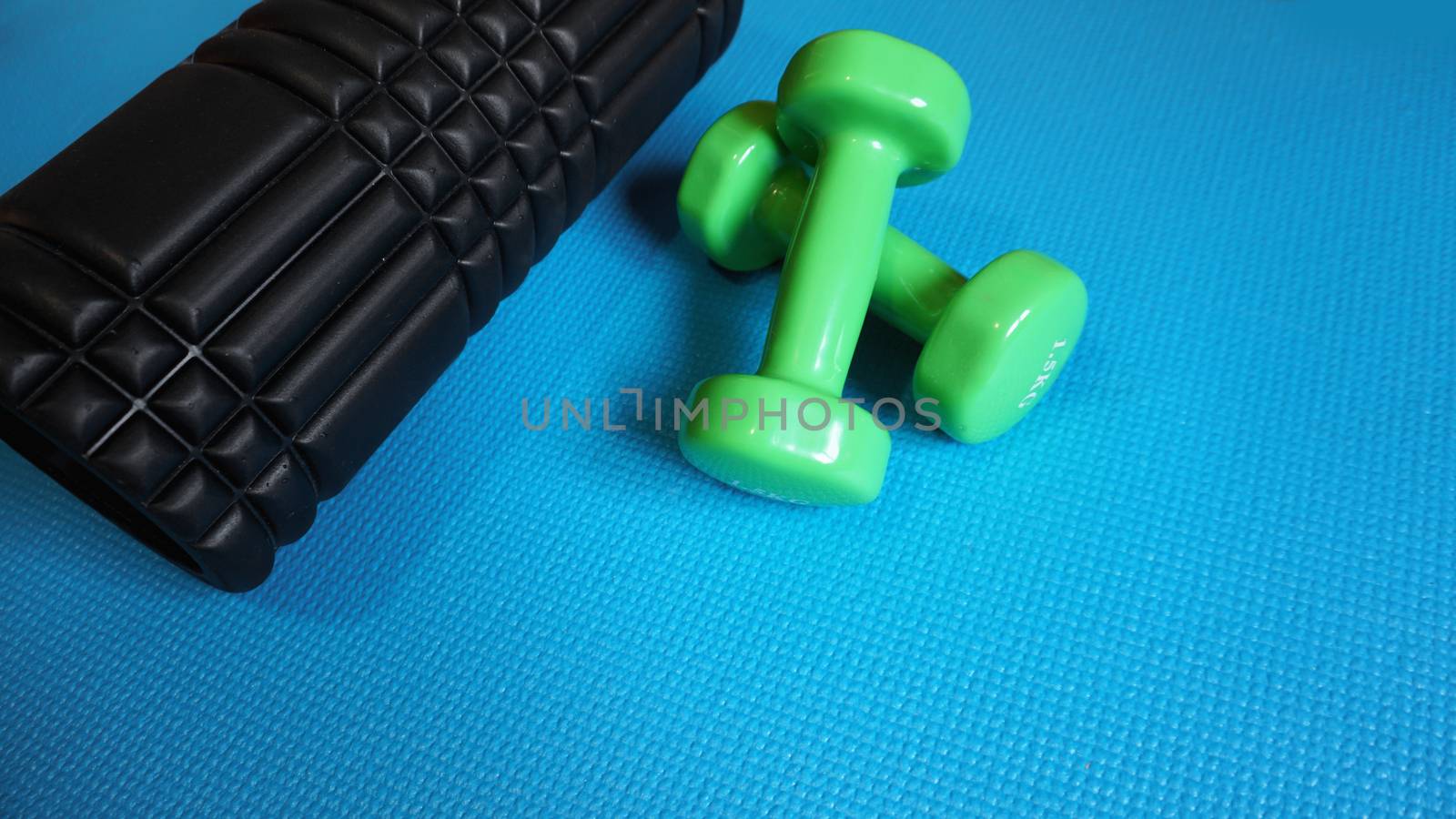 Foam Roller with green dumbbells Gym Fitness Equipment Blue background self Myofascial Release - MFR.