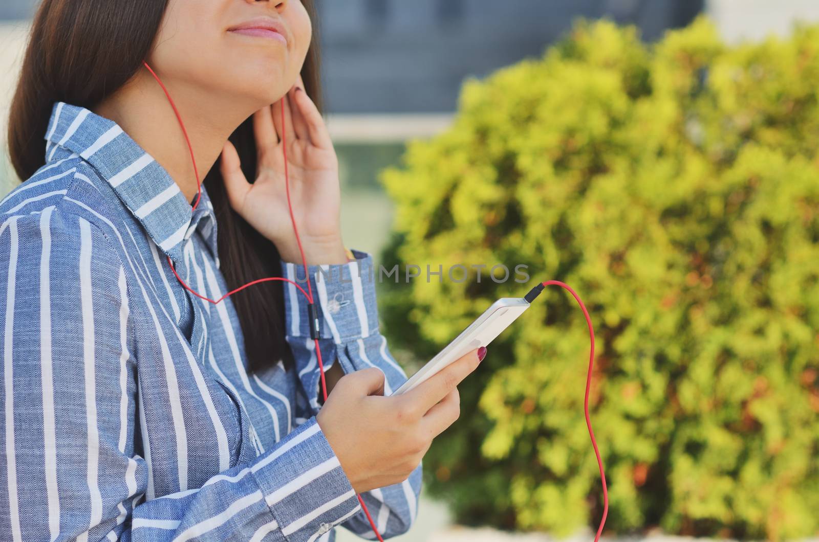 Young girl student holding a phone and listening to music on the street in the Park