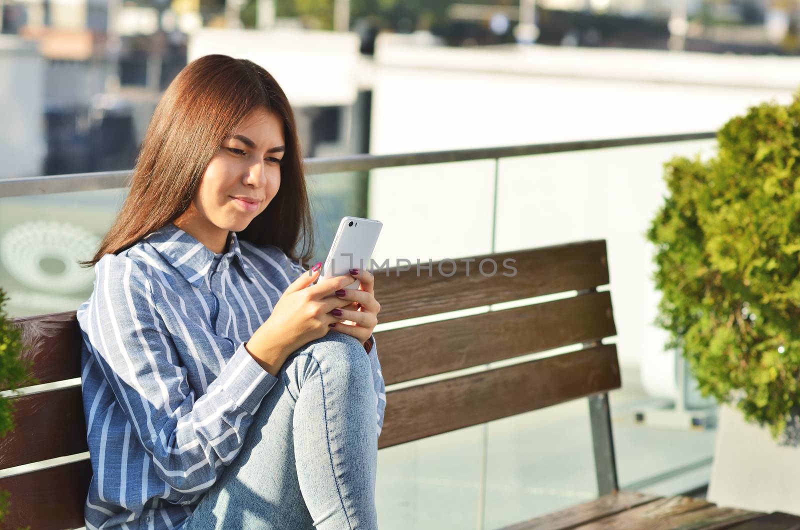 Portrait of a young girl who uses the phone while on the street near the shop